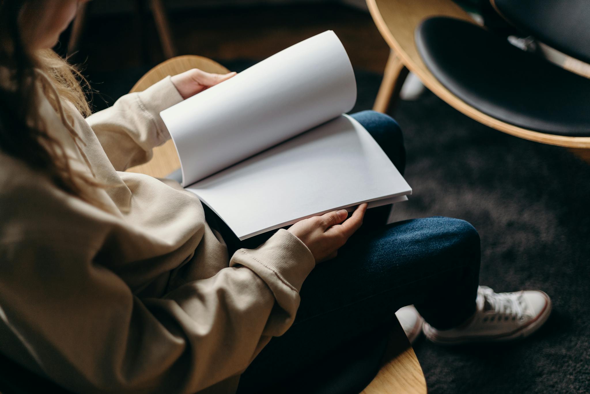 A person in a cozy home setting flips through a blank notebook, creating a relaxed and isolated atmosphere.