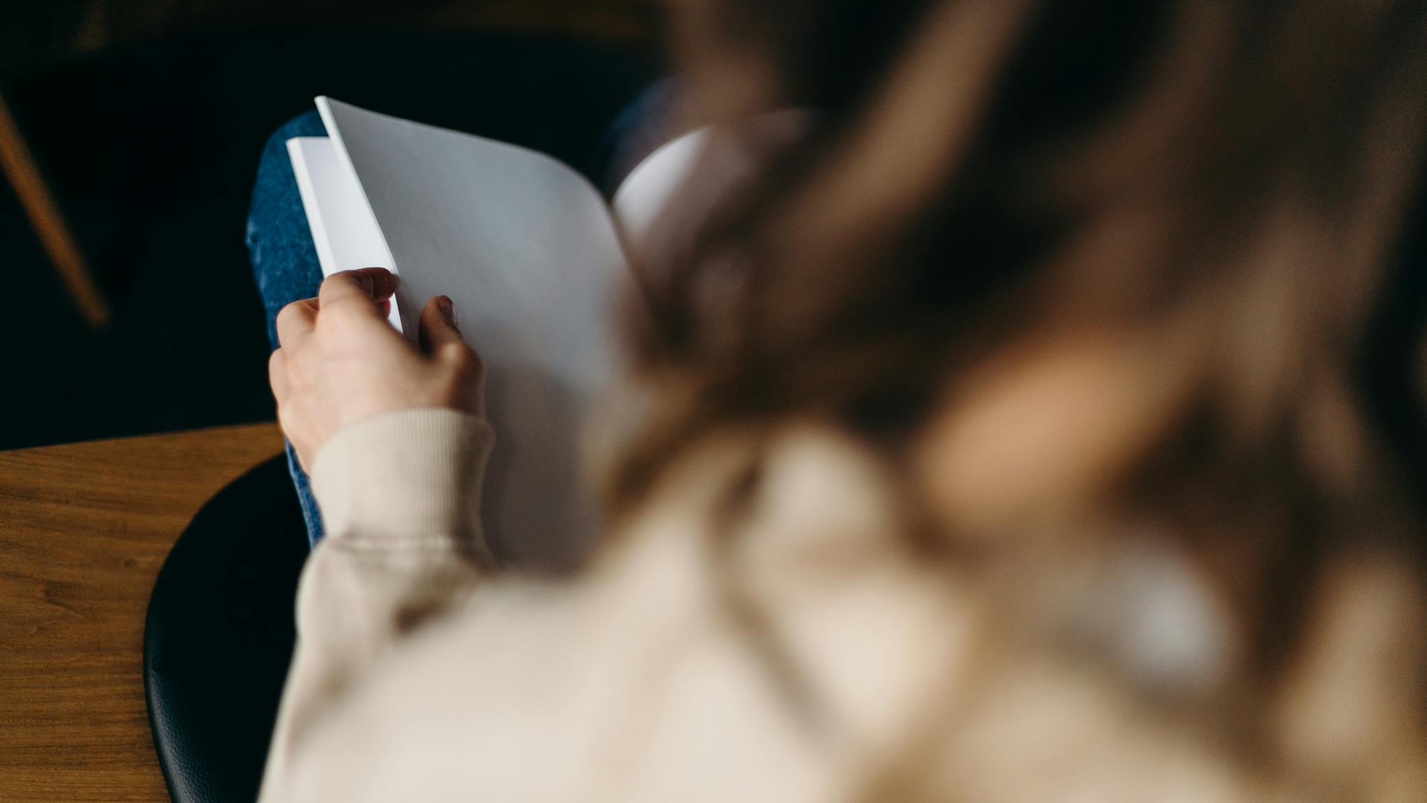 Close-up of an adult reading a blank notebook indoors, focused on the pages.